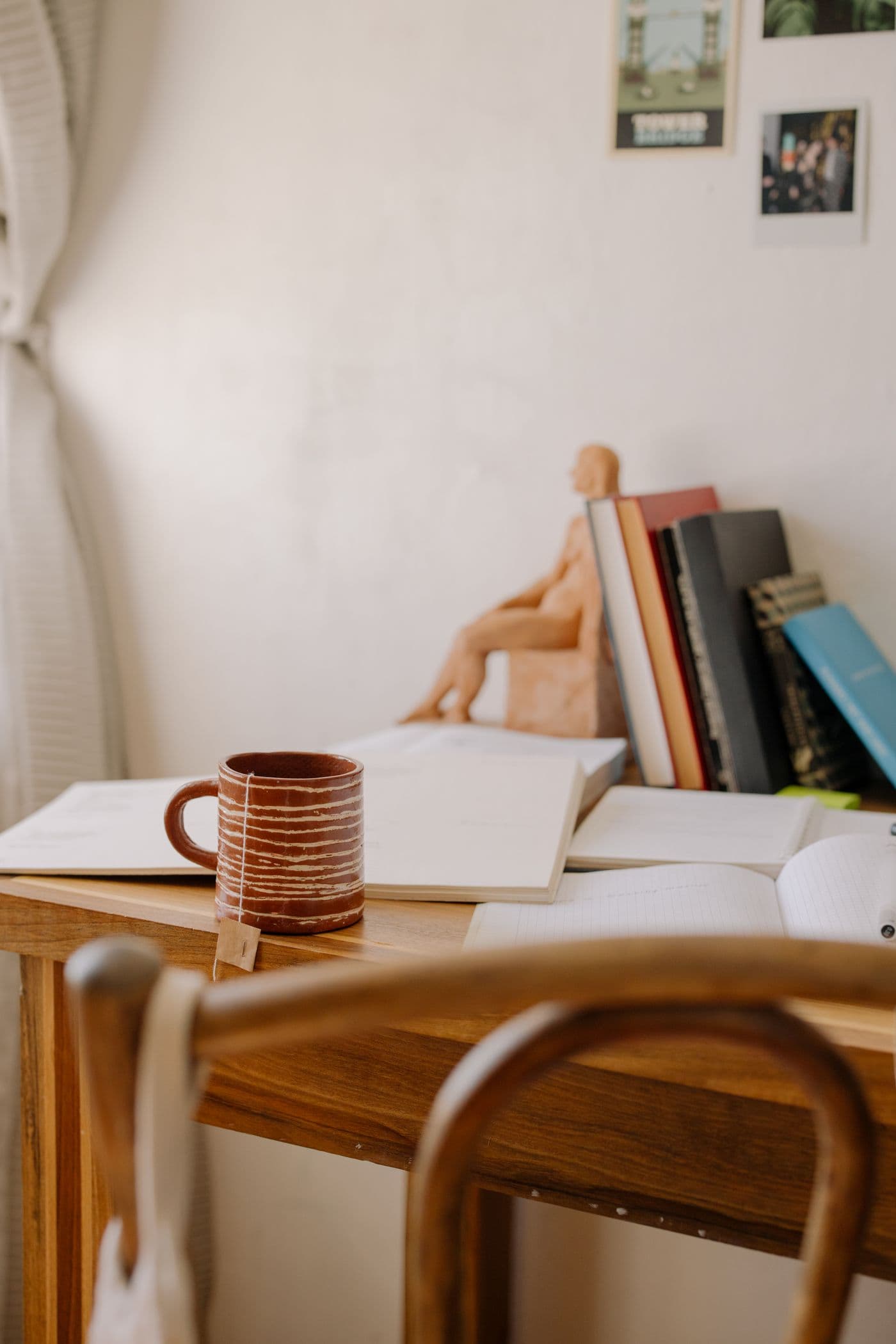 Una scrivania con libri, un quaderno aperto e una tazza di tè