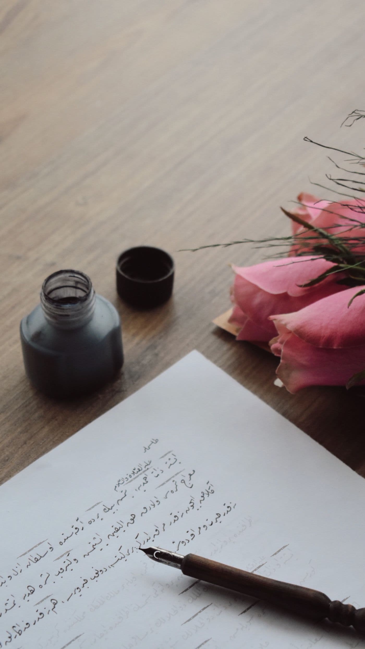 Una lettera scritta a mano, con calamaio e rose
