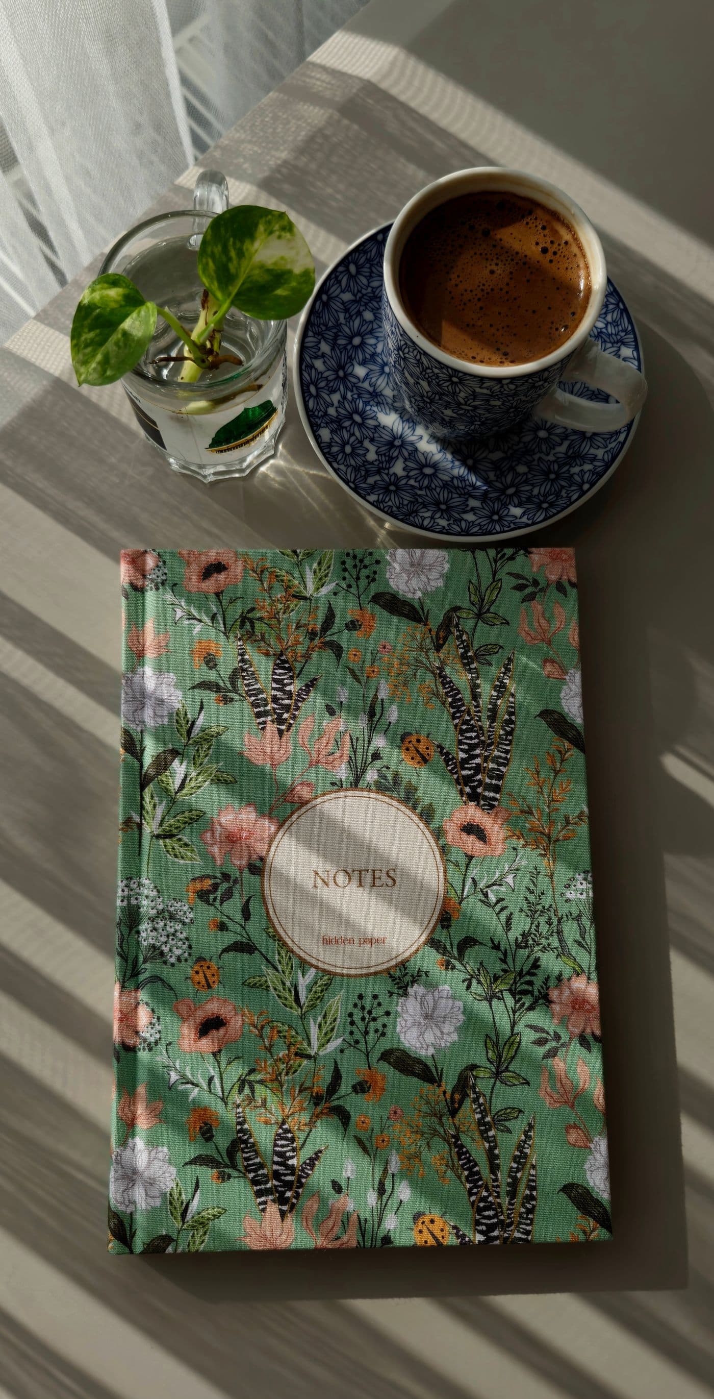 Un quaderno a fiori, una tazza di caffè e una pianta