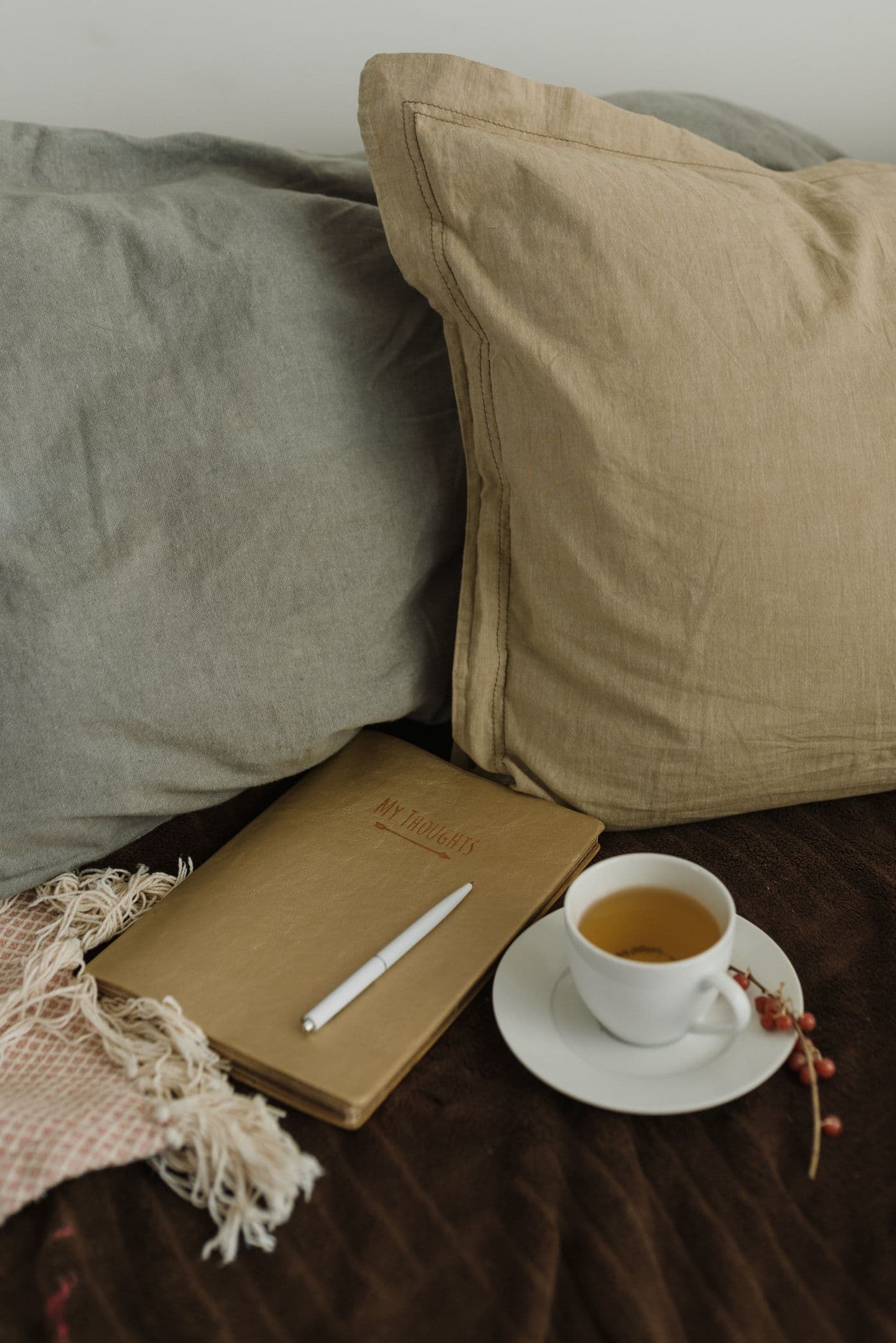 Una tazza di tè e un quaderno su un letto con i cuscini