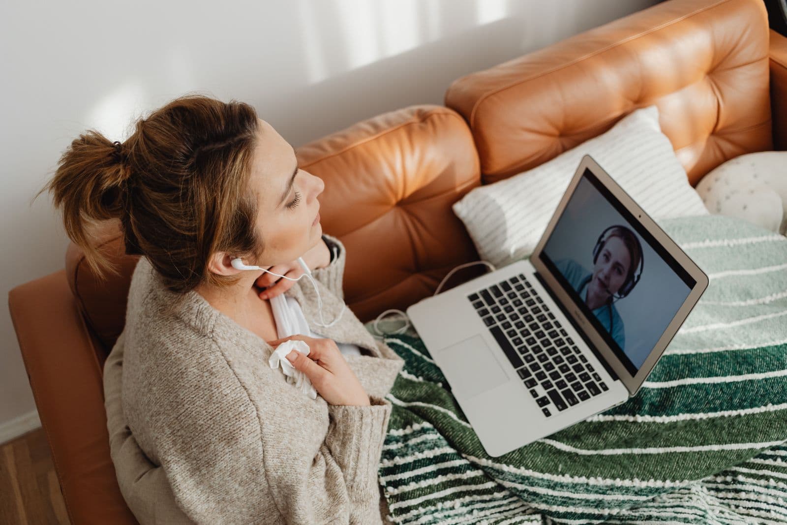 Una persona in videochiamata dal divano di casa, con le cuffie